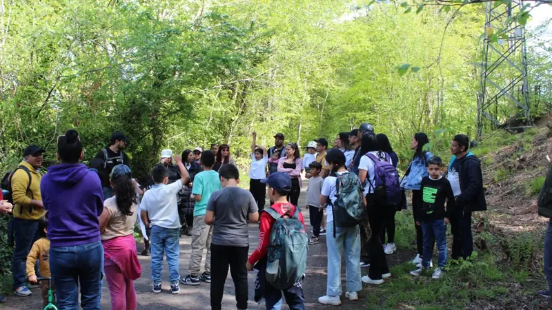 A large group of families gathered in a woodland clearing before a walk